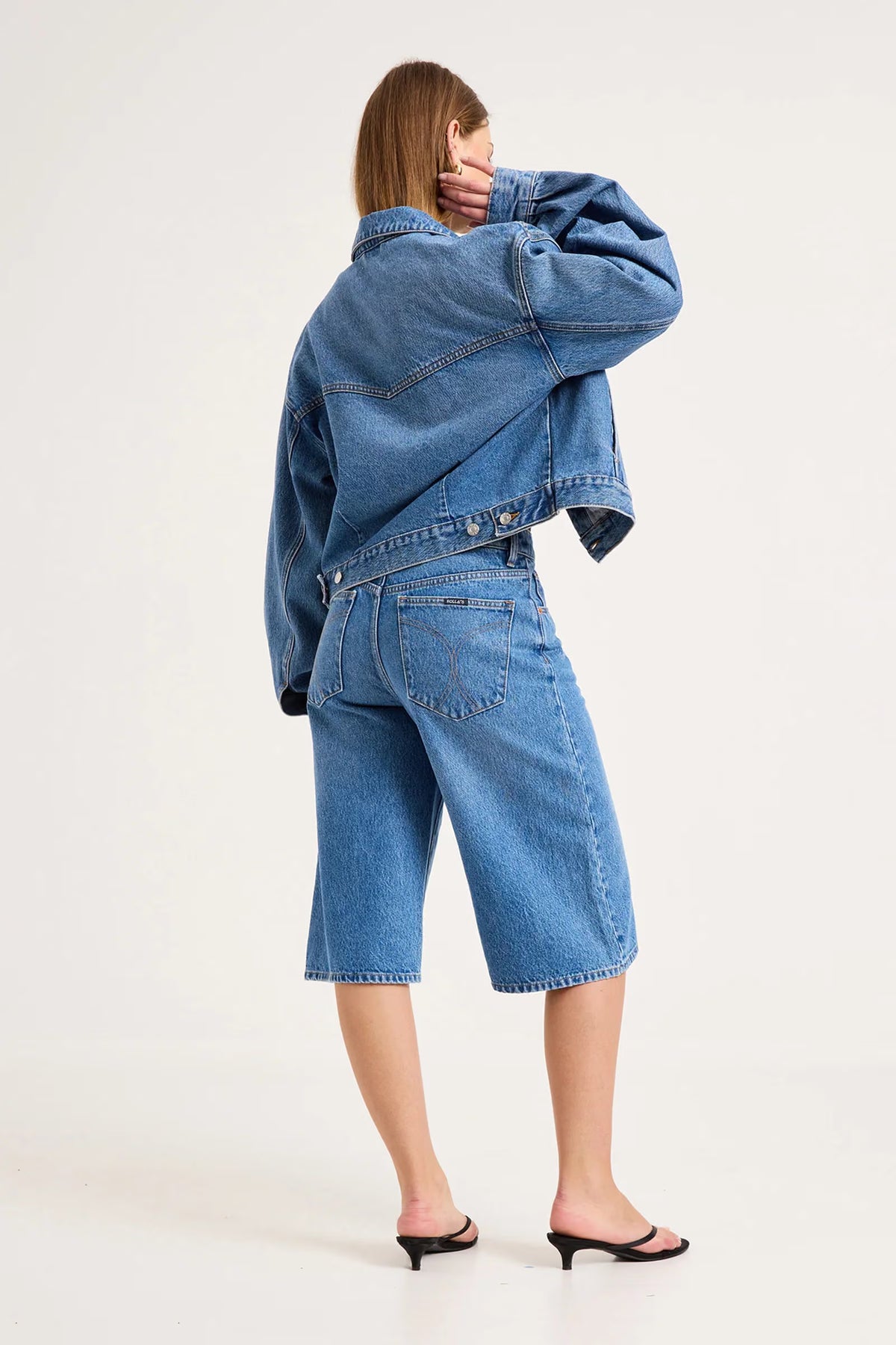 Back view of mid-blue denim culottes showing the square back pockets, waistband and contrast stitching.