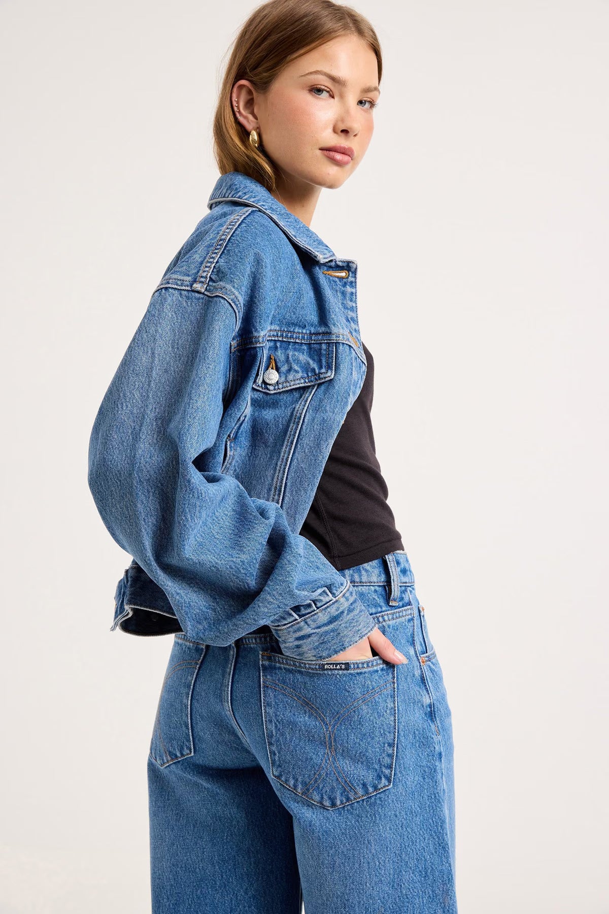Close-up side view of mid-blue denim culottes showing the wide-leg silhouette, waistband and side pocket details.
