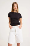 Close-up front view of white knee-length denim shorts showing the waistband, button closure, belt loops and front pockets.