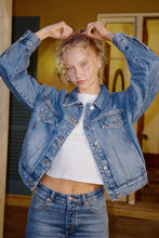 Model wearing the Soho Vintage blue denim swing jacket over a white cropped tee with matching jeans, showing the pointed collar, silver button front, chest pockets and oversized balloon sleeves, lifestyle front view