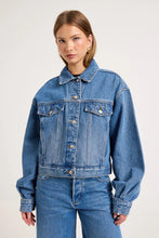 Model wearing the blue denim swing jacket with matching jeans, showing the pointed collar, structured chest pockets, silver buttons and relaxed cropped silhouette, front view
