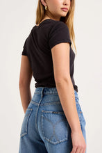 Close-up back view of the mid-blue jeans worn with a black tee, showing the square back pockets, contrast tobacco stitching, back yoke and relaxed seat.