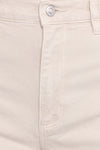 Close-up front detail of off-white denim showing the silver button, zip-fly closure, belt loop, stitching and curved edge of the front scoop pocket.