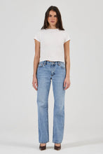Woman wearing a white t-shirt and light blue jeans on a white background