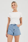 A full-length front view of mid-blue high-rise denim shorts styled with a plain white tee and brown heeled sandals.