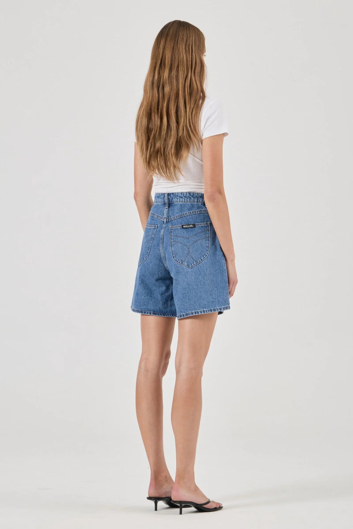 Blue denim shorts shown from the back with two shaped back pockets and contrasting stitching.