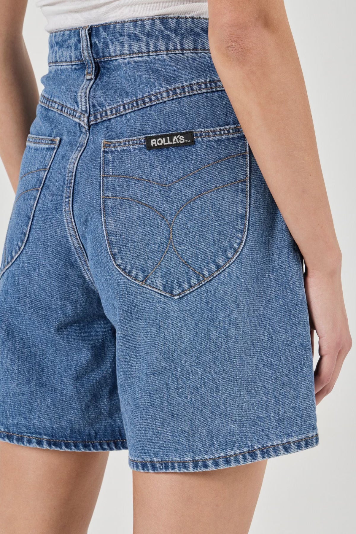 Close-up back view of blue denim shorts showing the shaped back pockets, contrasting stitching and waistband.
