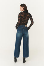 Woman wearing a black lace top and blue jeans on a white background