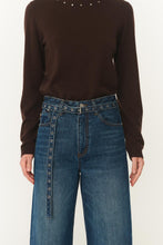 Person wearing a brown sweater and blue jeans on a white background