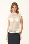A woman wears a bone crochet top with floral motifs and a dark midi skirt in a front view.
