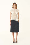 A woman wears the bone crochet top with a dark midi skirt in a full-length front view.
