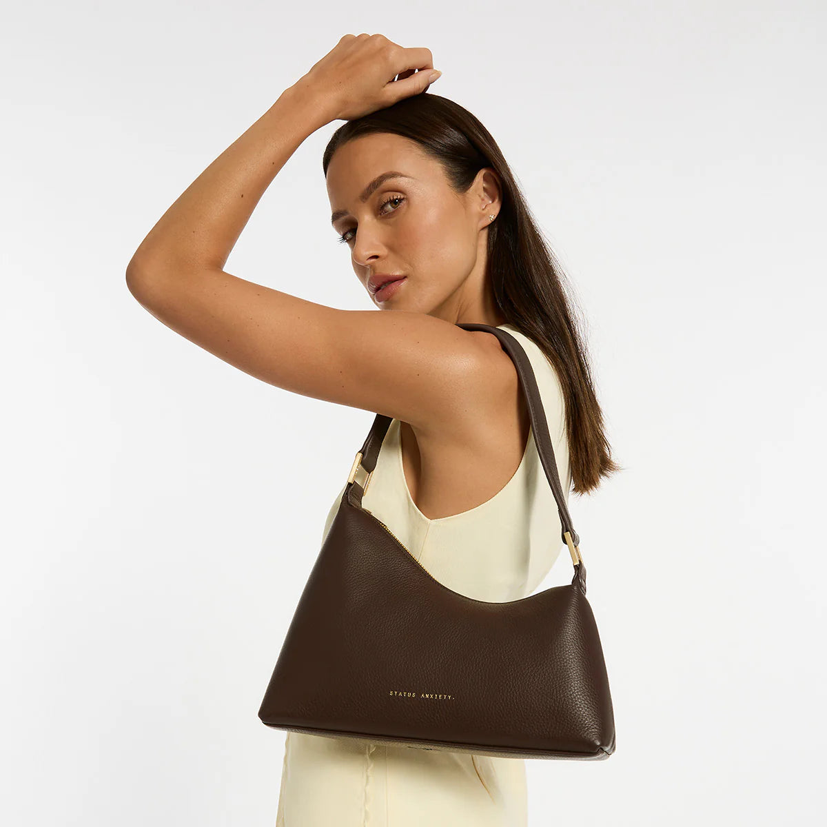 Status Anxiety Reverie Bag Cocoa — the Reverie Bag in Cocoa with brushed gold hardware by Status Anxiety is an easy statement piece with a clean, sculptural shape.