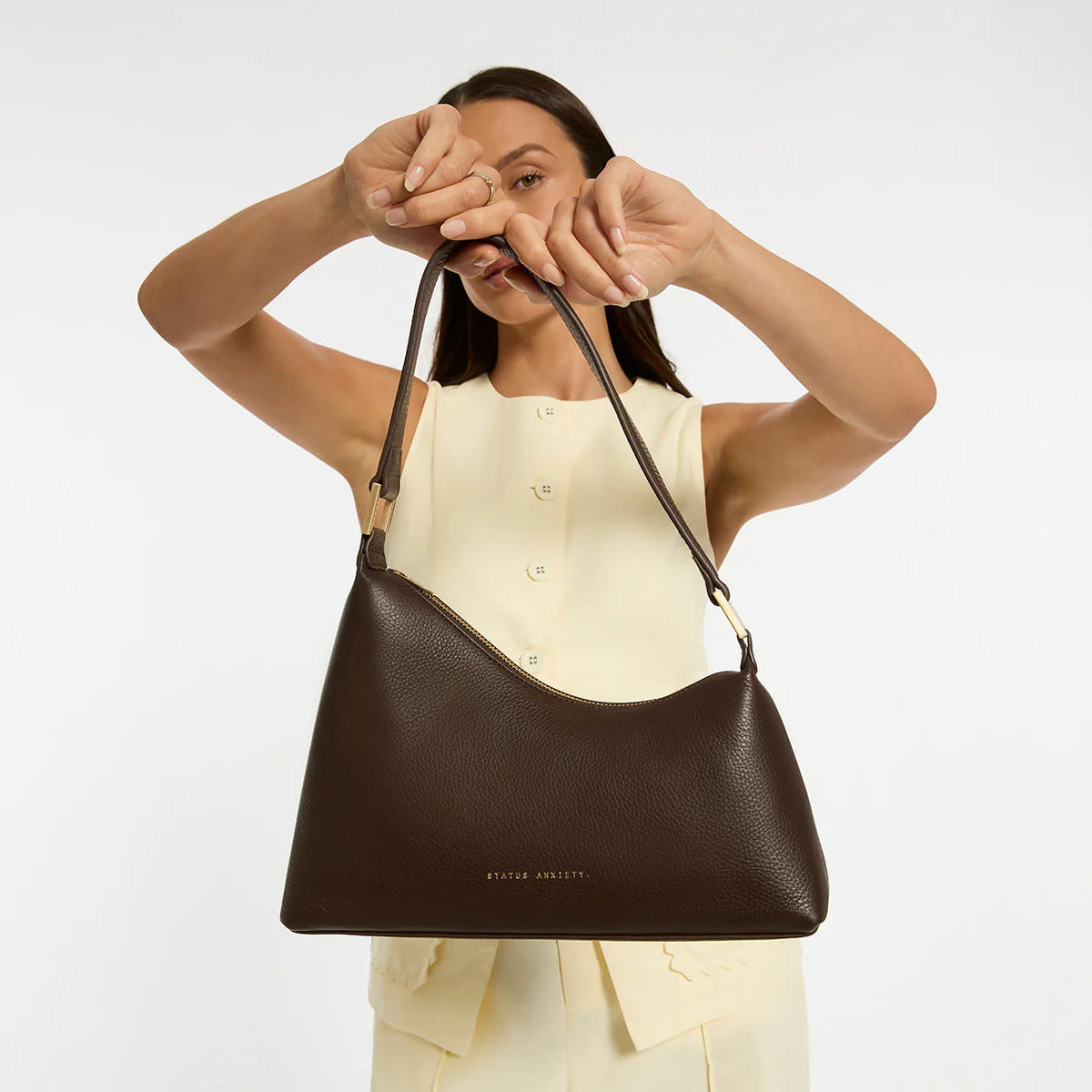 Status Anxiety Reverie Bag Cocoa — the Reverie Bag in Cocoa with brushed gold hardware by Status Anxiety is an easy statement piece with a clean, sculptural shape.