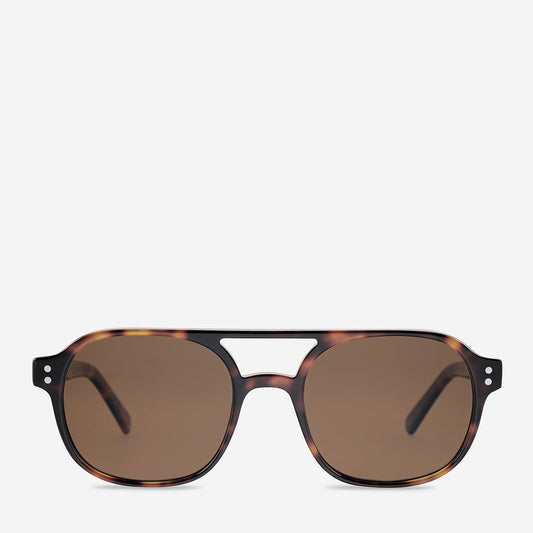 Brown tortoiseshell sunglasses shown from the front, featuring a softly rounded rectangular frame, warm mottled brown pattern, dark brown tinted lenses, a narrow central bridge and slim temples extending from the sides.