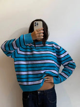 Person wearing a blue and white striped sweater against a plain background