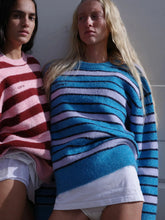 Two women wearing colorful striped sweaters against a neutral background