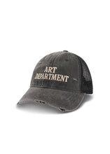 Three-quarter product view of the washed black trucker cap showing the embroidered Art Department lettering, distressed curved peak and black mesh back.