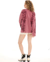 The red oversized long-sleeve tee is shown from the back with rose graphics across the shoulders and sides.