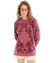 A model wears the red rose-print long-sleeve tee in a closer front view showing its oversized fit.