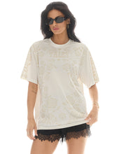 A model wears the off-white floral graphic T-shirt in a front studio view with sunglasses and black shorts.
