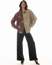 A model wears the embellished brown and beige striped shirt with black wide-leg trousers in a full-length front view.
