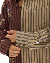 A close-up shows the striped chest pocket, button front and embellished buttoned cuff.