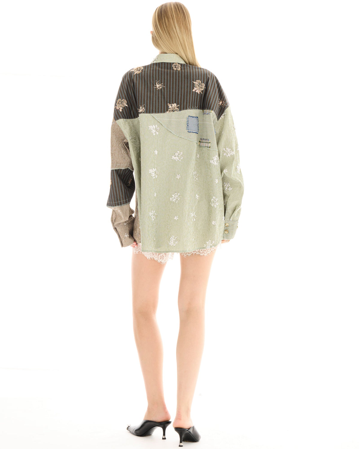 Back view of a woman wearing a sage green oversized patchwork shirt, showing the contrasting charcoal, taupe and tan panels and denim patch at the back yoke.