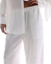 A close-up shows the elasticated drawstring waistband and tonal floral pattern on the white pants.
