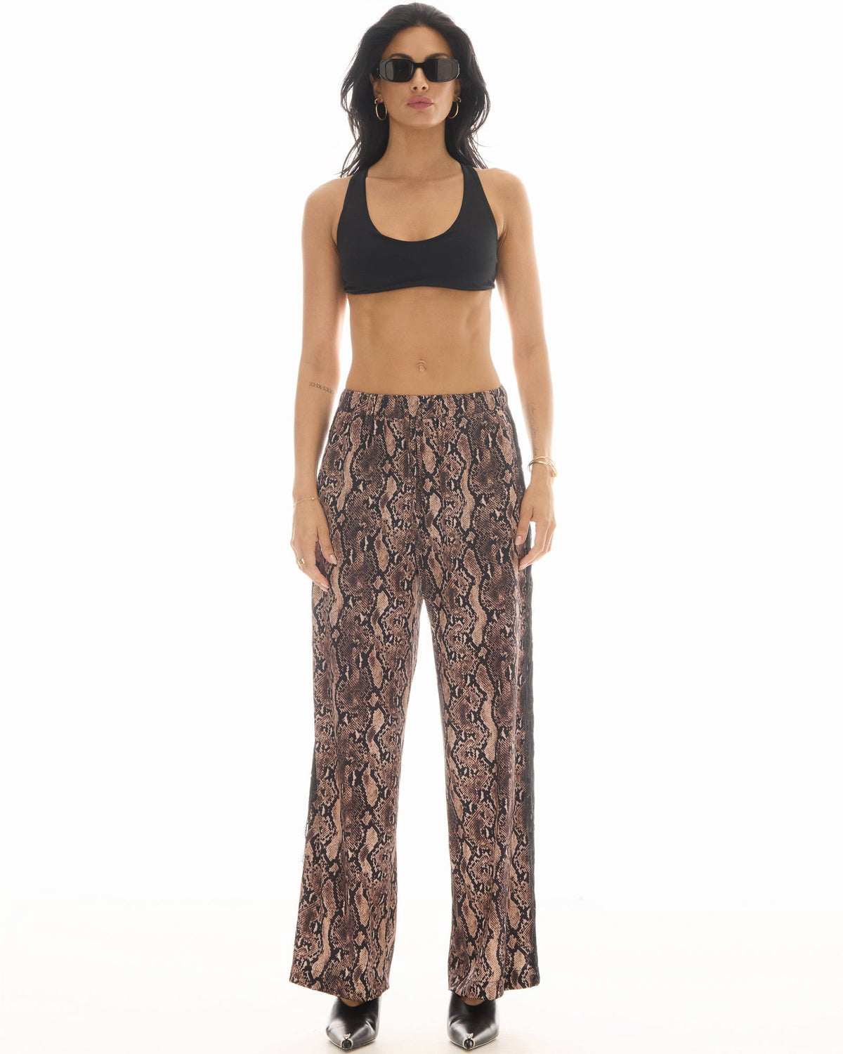 Front view of the wide-leg snake-print pants styled with a black crop top, showing the relaxed pull-on silhouette.