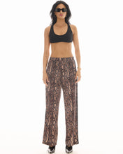 Front view of the wide-leg snake-print pants styled with a black crop top, showing the relaxed pull-on silhouette.