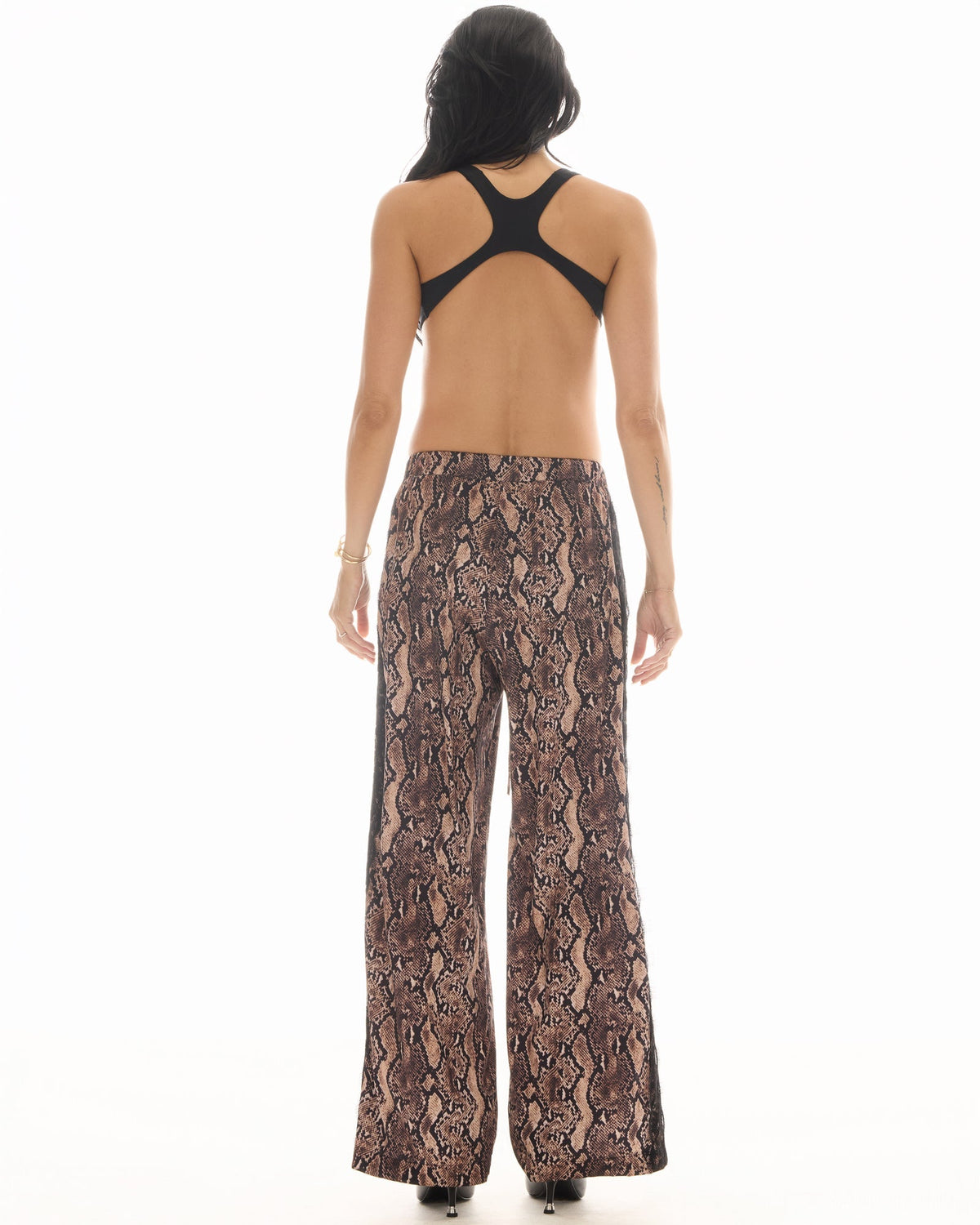 Back view of the snake-print pants showing the relaxed wide legs and tuxedo lace trim along the side seams.