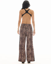 Back view of the snake-print pants showing the relaxed wide legs and tuxedo lace trim along the side seams.