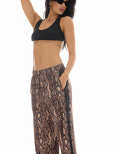 Close side pose highlighting the snake-print satin finish, relaxed waist and side pocket detail.