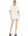Back view of a white oversized T-shirt with green ribbed neckline and sleeve cuffs, showing a small orange graphic near the lower back
