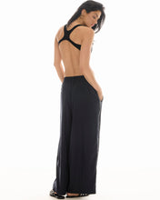 A model wears the black wide-leg pinstripe pants in a rear view showing the elasticated waist and relaxed fit.
