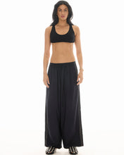 A model wears the black pinstripe pants with a cropped black top in a full-length front studio view.

