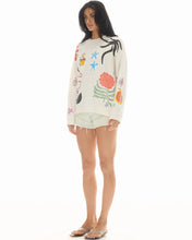 Woman wearing a colorful floral sweater and shorts on a white background