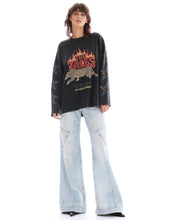 Full-length front view of the oversized graphic long sleeve tee styled with light-wash wide-leg jeans against a white studio background.