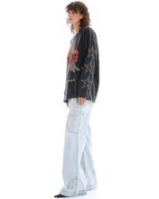 Side view showing the relaxed oversized silhouette and leopard-print star graphics running along the long sleeve.