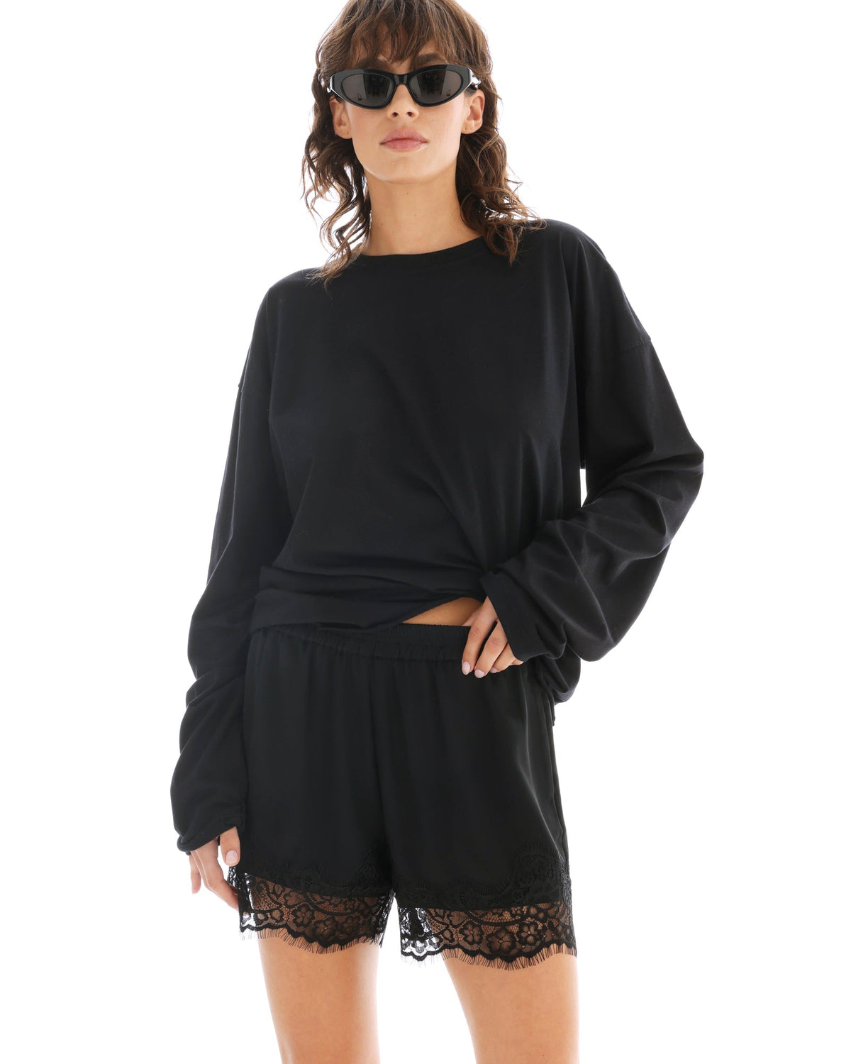 The model wears black lace-trimmed shorts with a cropped black top and oversized jacket.