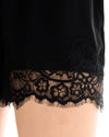Close-up view of the black shorts showing the decorative Chantilly lace hem.