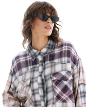 A close-up shows the shirt’s collar, button-through front and contrasting plaid chest pockets.