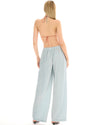 Back view of a woman wearing pale ice blue wide-leg lurex pants, showing the elasticated waistband and full-length loose silhouette.