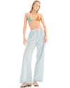 A woman wearing pale ice blue lurex pants in a relaxed front three-quarter pose, showing the wide-leg shape and subtle metallic shimmer.