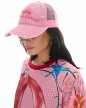 Side lifestyle view showing the distressed curved peak, embroidered slogan and pink mesh back while worn with sunglasses.