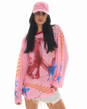Front lifestyle view of the pink slogan trucker cap styled with sunglasses, a colourful oversized mesh top and white shorts.